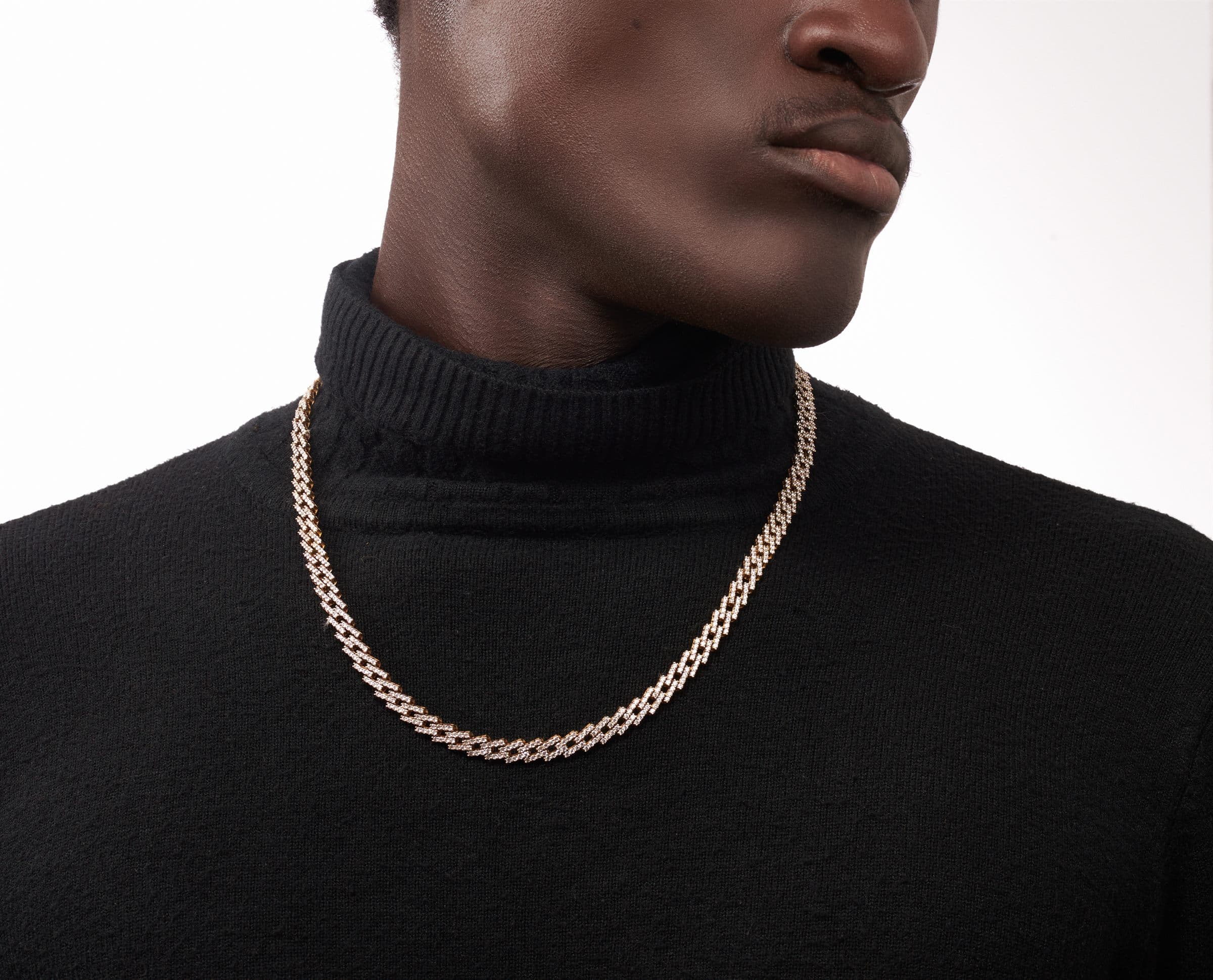 Gold curb chain worn over a black turtleneck, shot close